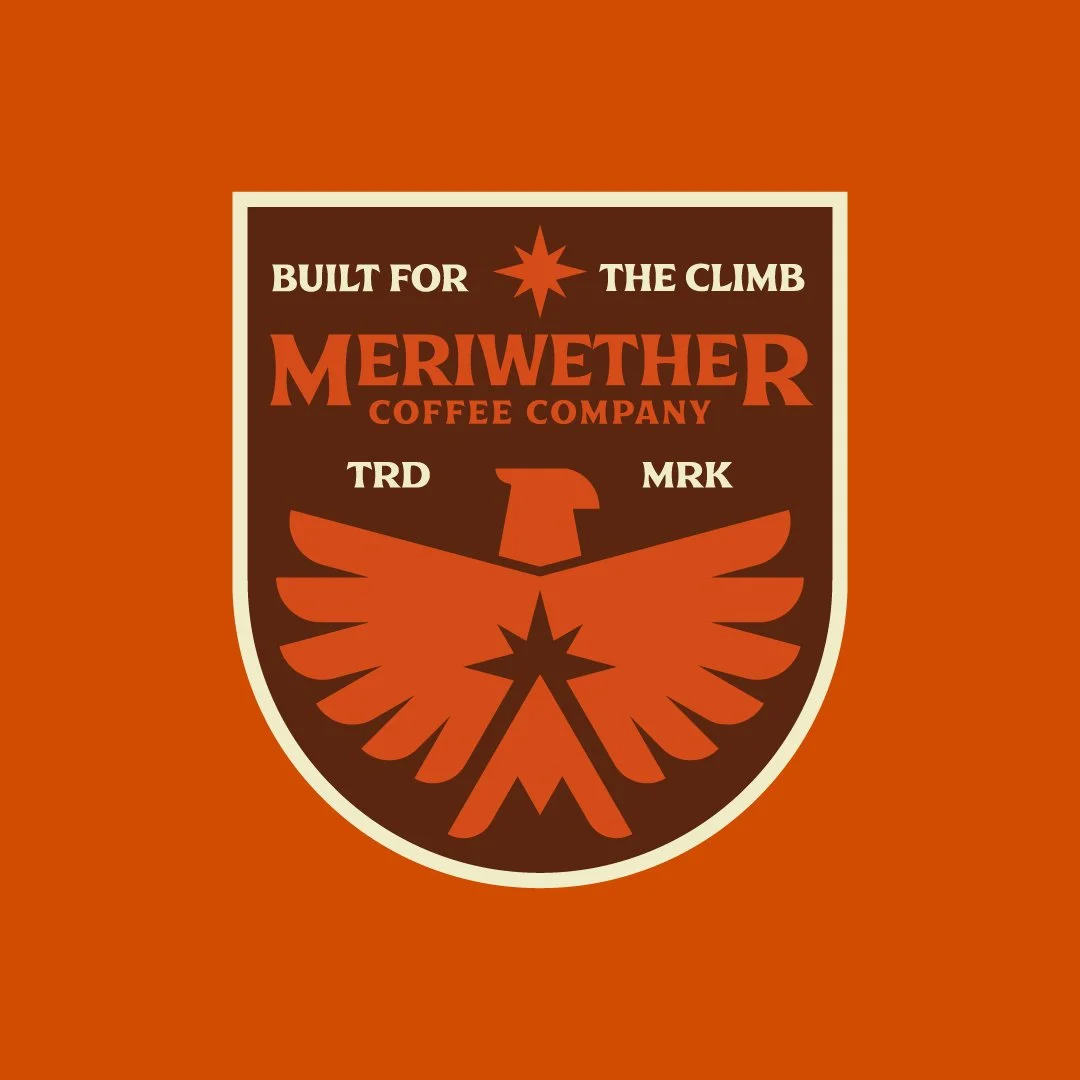 A logo of Meriwether Coffee Company featuring a shield with an eagle, text "Built for the climb," "TRD," and "MRK."