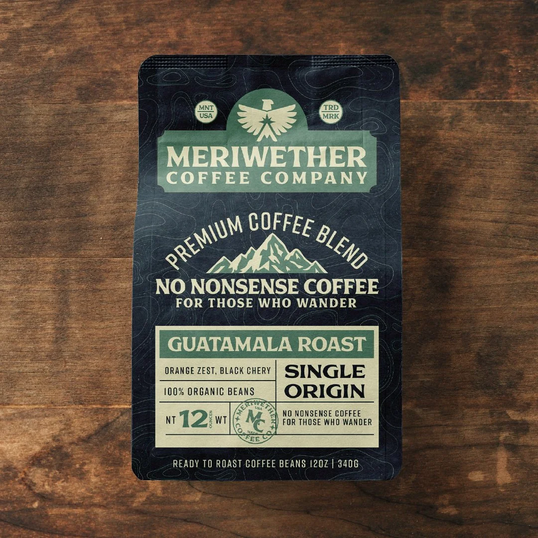 Package of Meriwether Coffee Company's Guatemala Roast premium coffee blend, single origin, 12 ounces, with organic beans and mountain-themed design on a wooden surface.