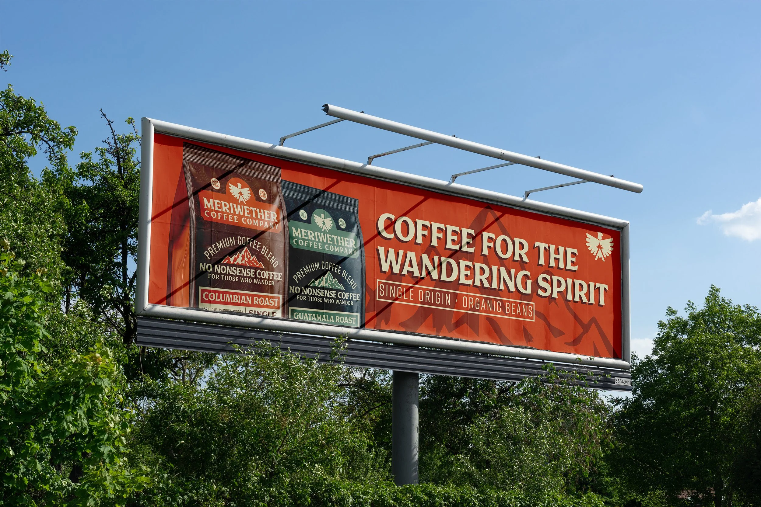 Billboard advertising Meriwether Coffee Company with two coffee bags, one labeled Columbian Roast and the other Guatemala Roast, and the slogan 'Coffee for the Wandering Spirit' against a clear blue sky.