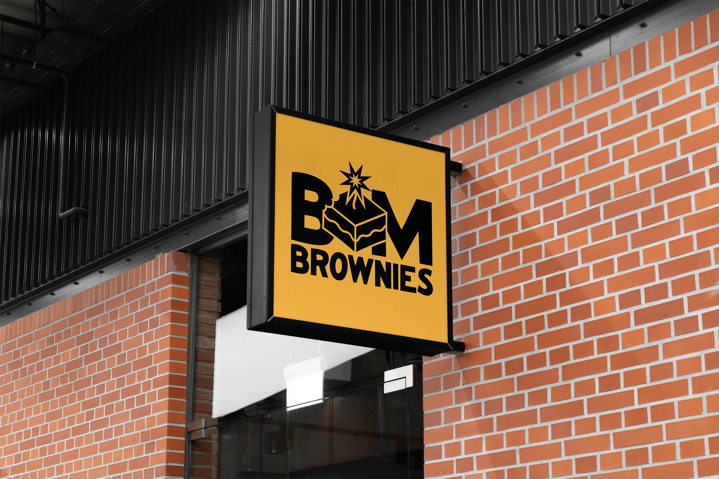 Sign for Bam Brownies with a yellow background, black text, and a graphic of a brownie with a bomb explosion