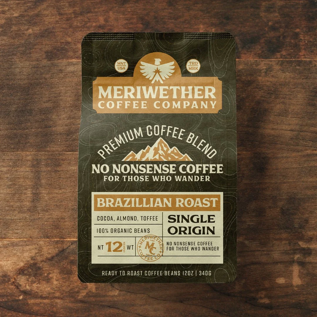 Packaging of Meriwether Coffee Company Brazilian Roast single-origin coffee beans, 12 ounces, with a black and brown design on a wooden surface.