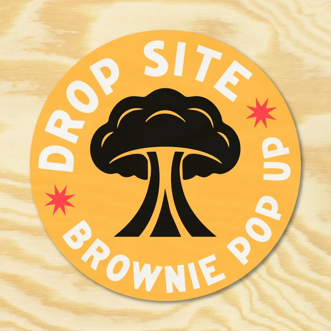 A sticker with a black mushroom cloud graphic. The text around the cloud reads 'Drop Site BROWNIE POP' in white letters on a yellow background, with red starburst symbols on either side.
