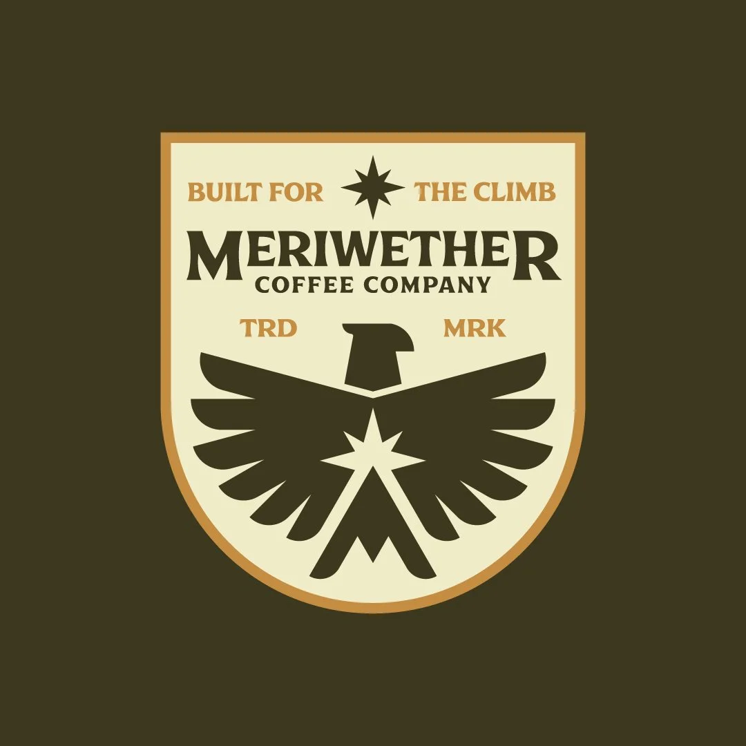 Coffee company's logo featuring a shield with the text "Built for the climb" and "Meriwether Coffee Company," a stylized eagle with outstretched wings.