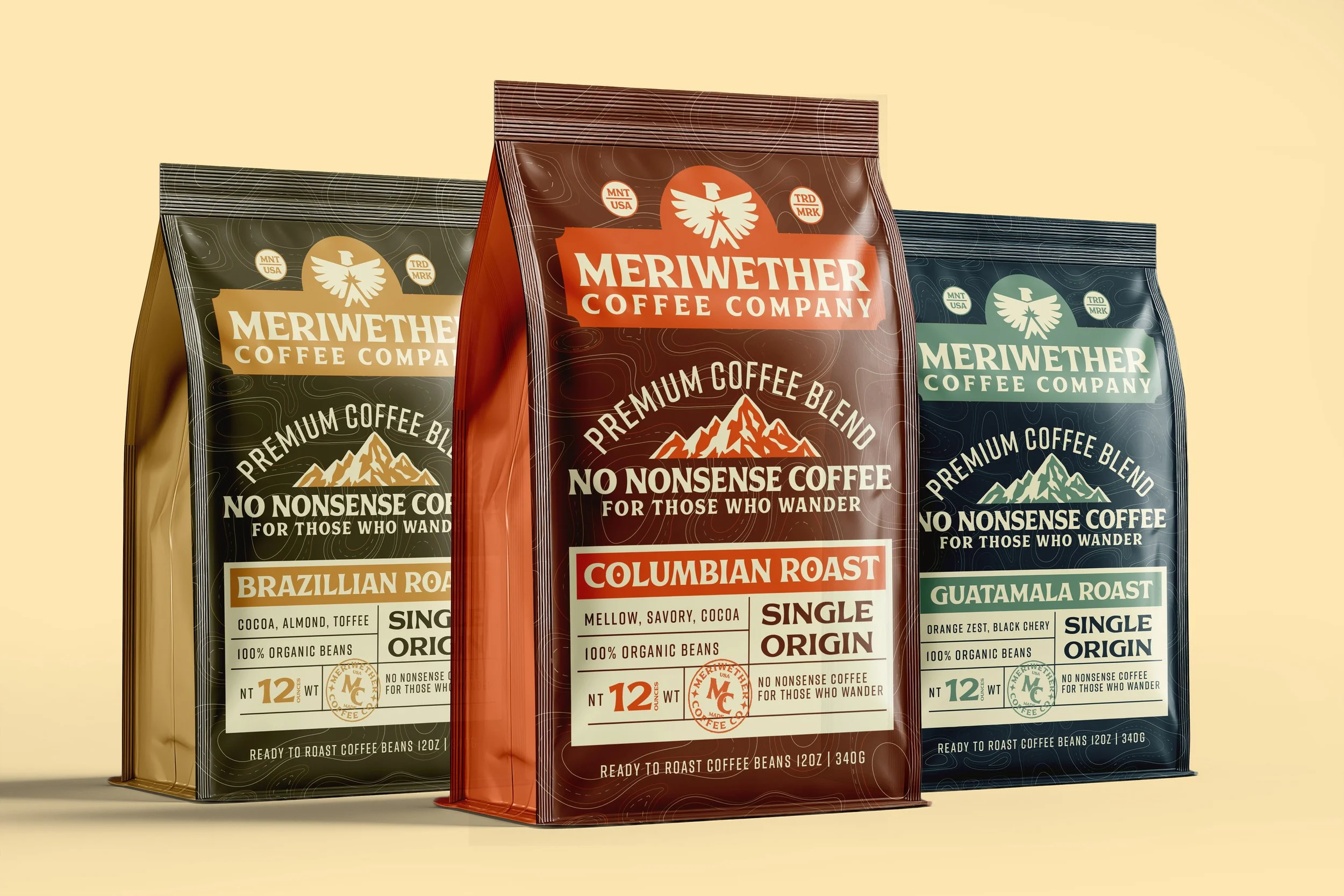 Three bags of Meriwether Coffee Company coffee beans in different flavors: Brazillian Road, Columbian Roast, and Guatemalan Roast, standing upright on a beige background.