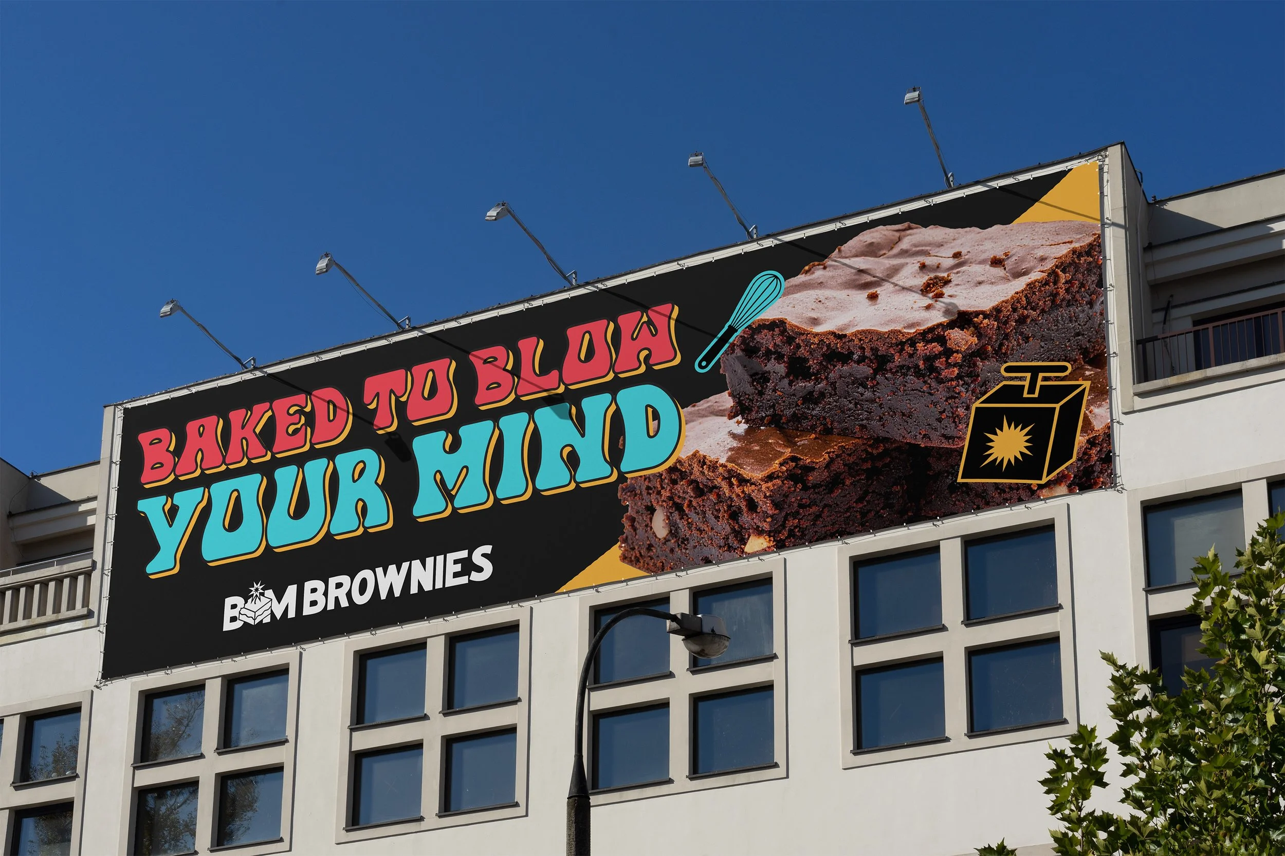 Billboard advertisement for baked brownies from Bomb Brownies featuring a large chocolate brownie with a spoon, a carton with a sun logo, and colorful text that says 'Baked to Blow Your Mind'.