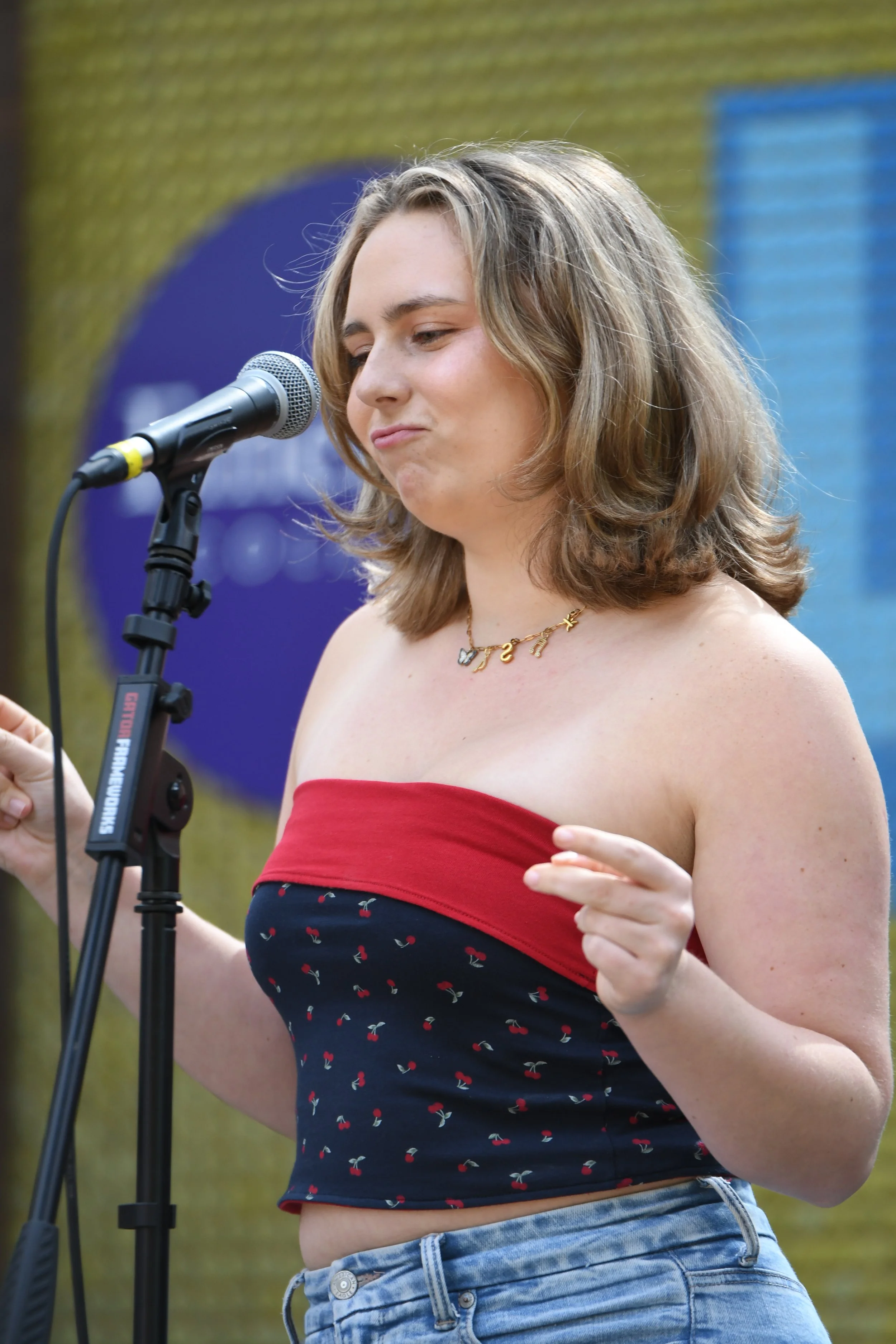 Woman singing or speaking into a microphone at an outdoor event.