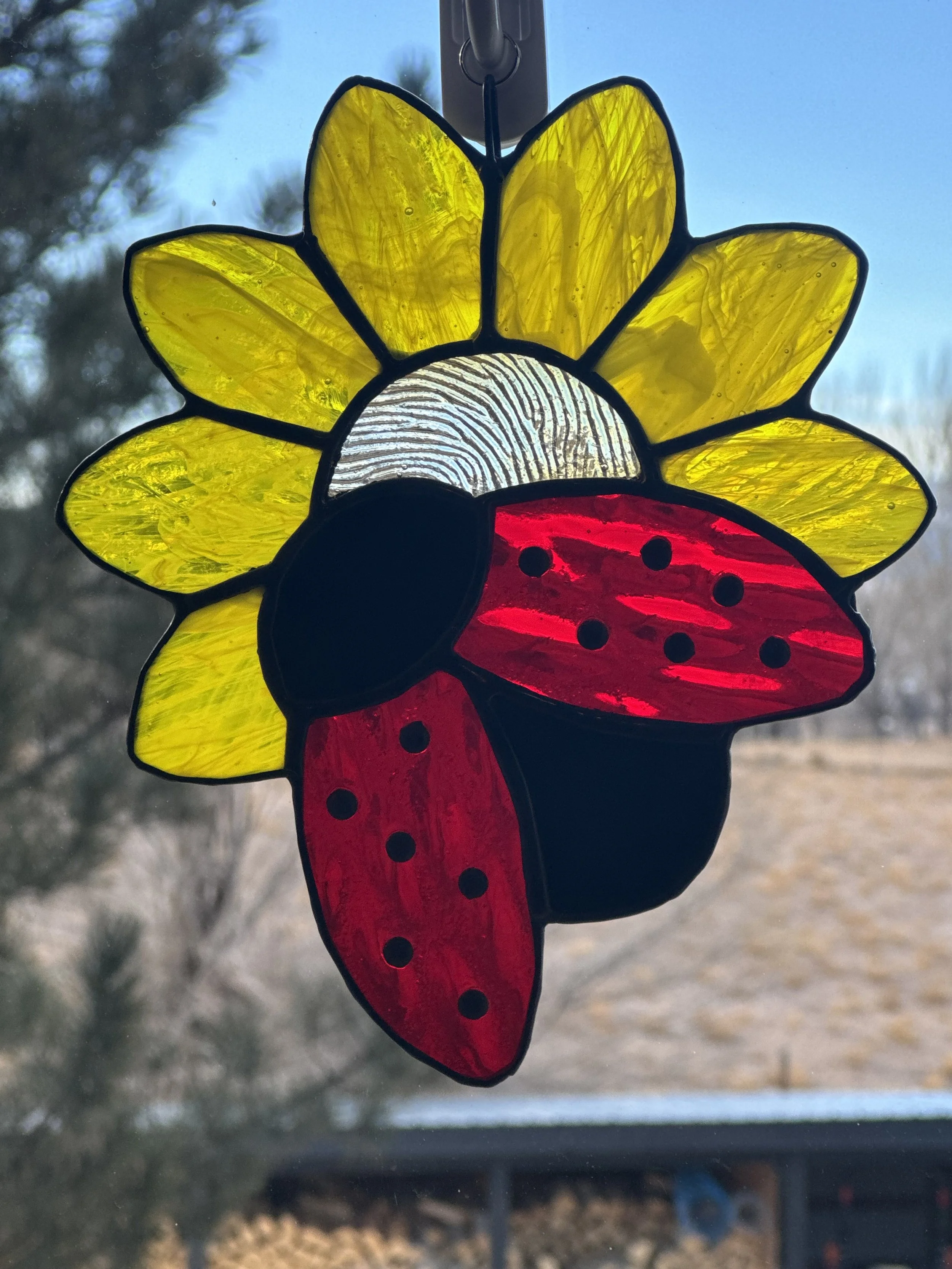 Colorful stained glass sun and ladybug hanging decoration.