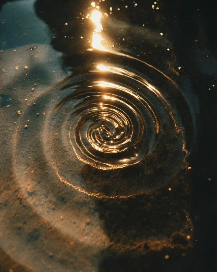 Close-up of a shiny, swirling liquid surface with reflections and ripples creating a spiral pattern.