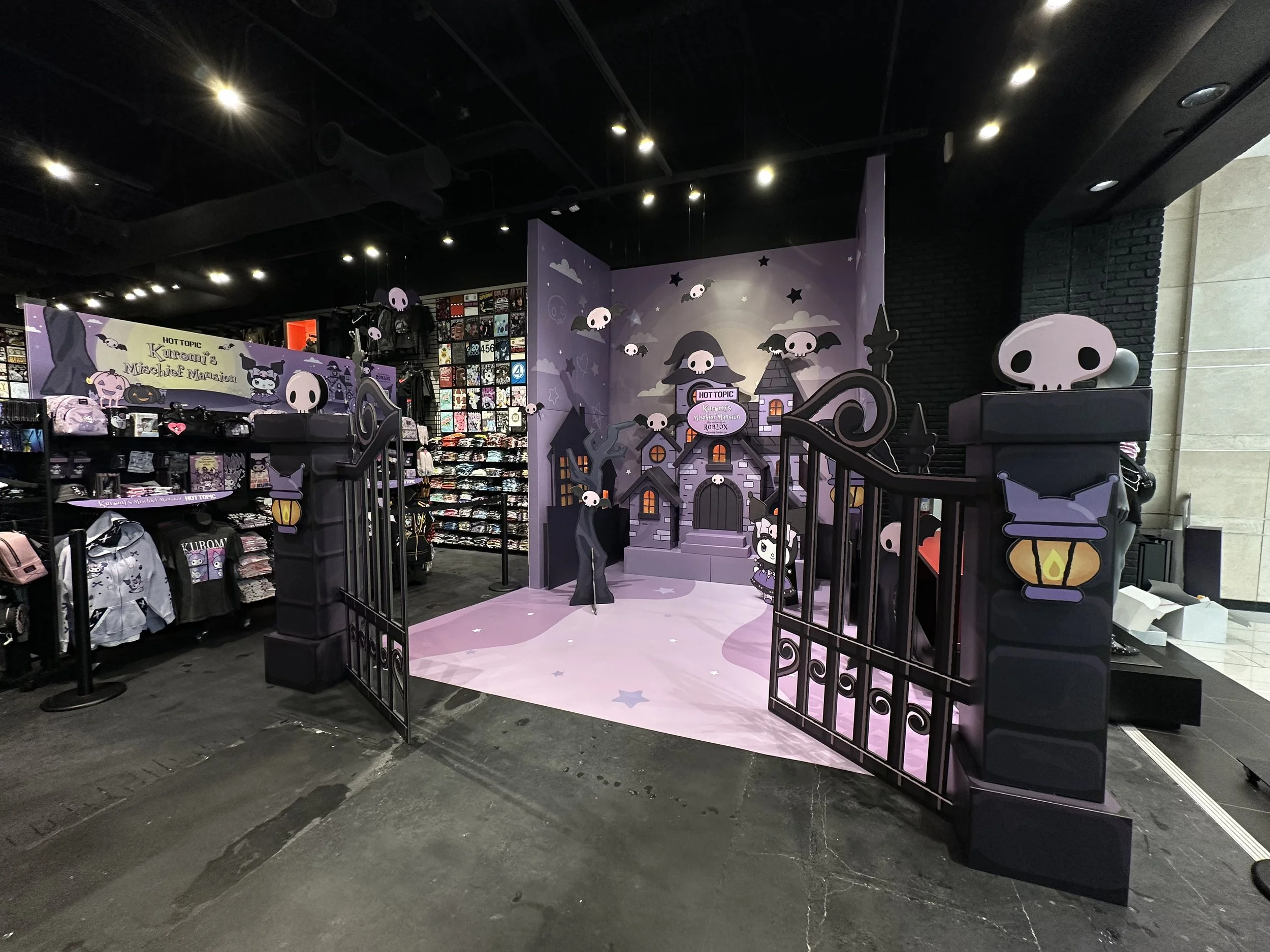Purple themed Halloween display in a retail store featuring cartoon skulls, haunted house backdrop, and Halloween decorations.
