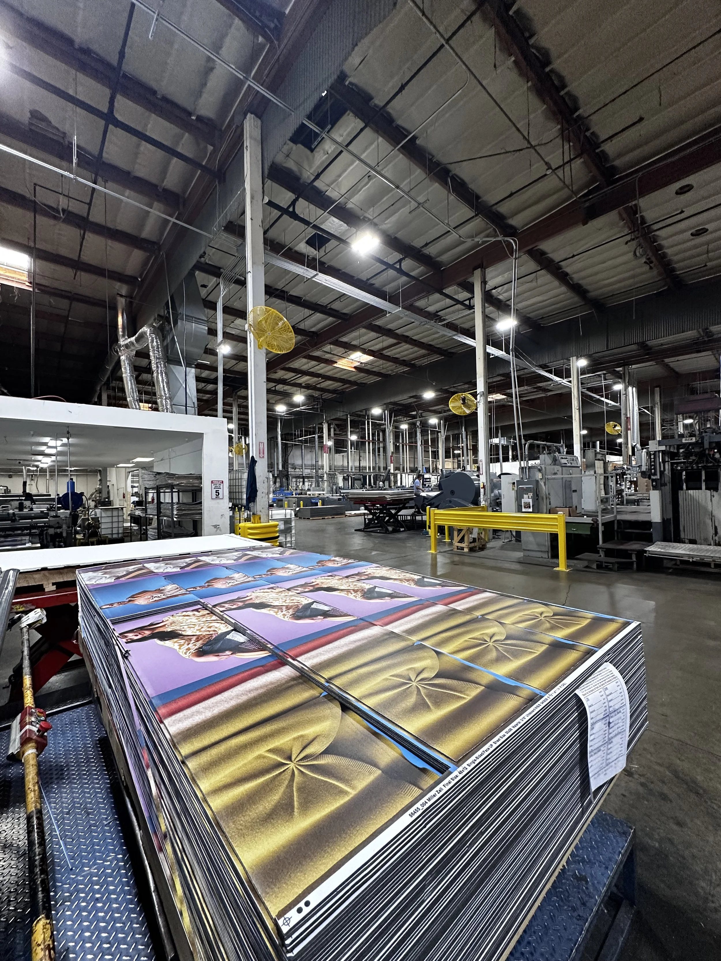 Stacks of printed posters or banners on a production line in a large industrial printing facility.