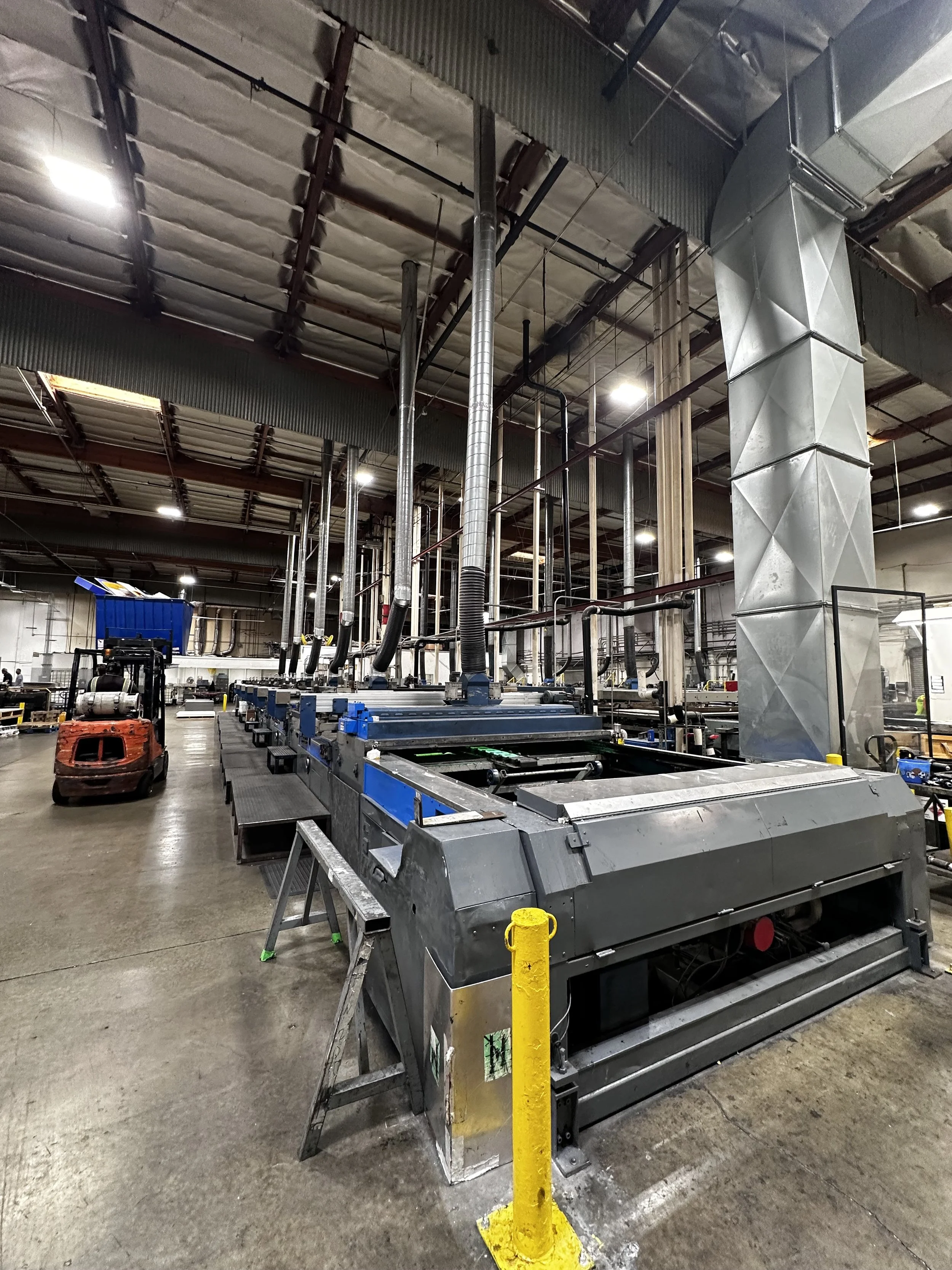 Industrial factory with large machinery, pipes, and ventilation system in a spacious warehouse.