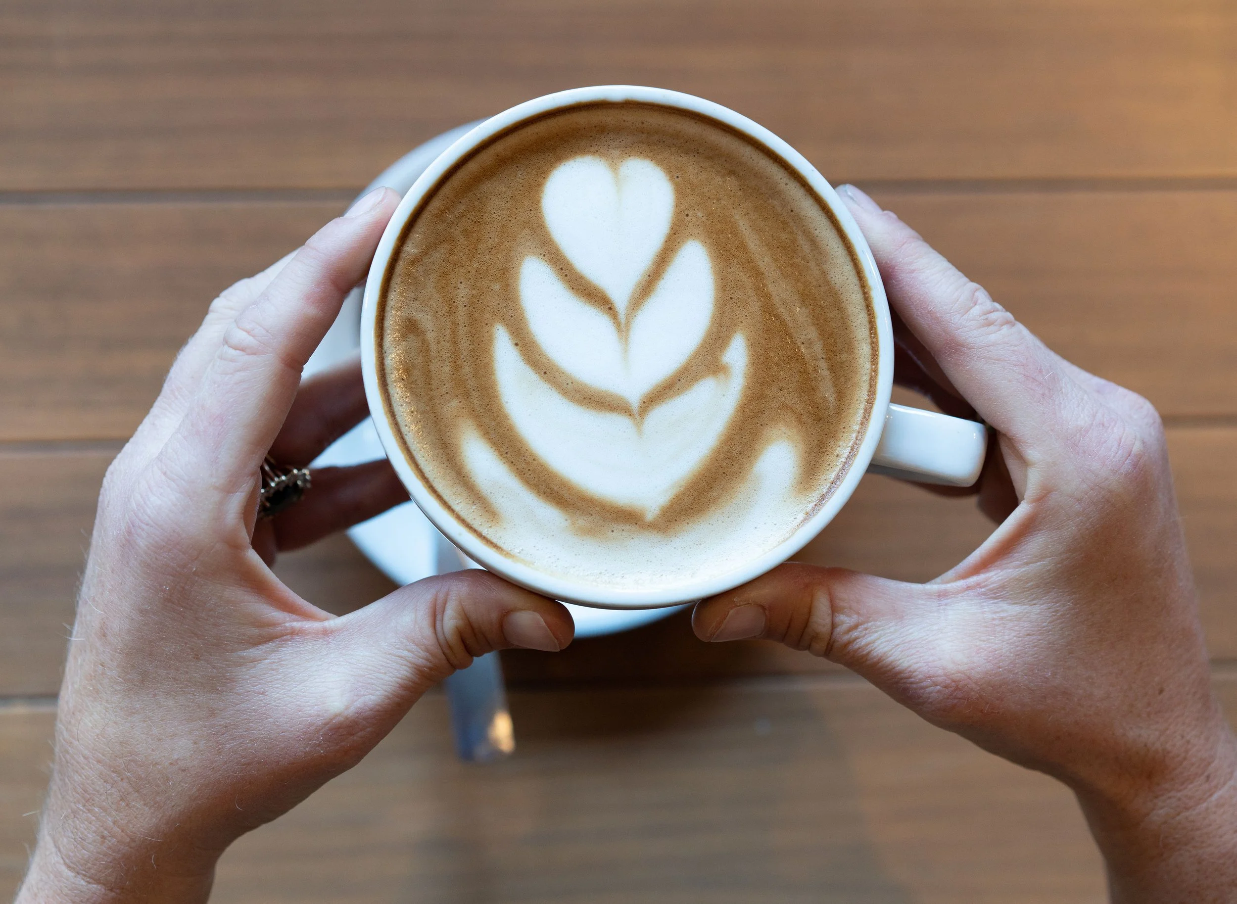 Literati Cafe Organic Latte with Foam Art held in hands