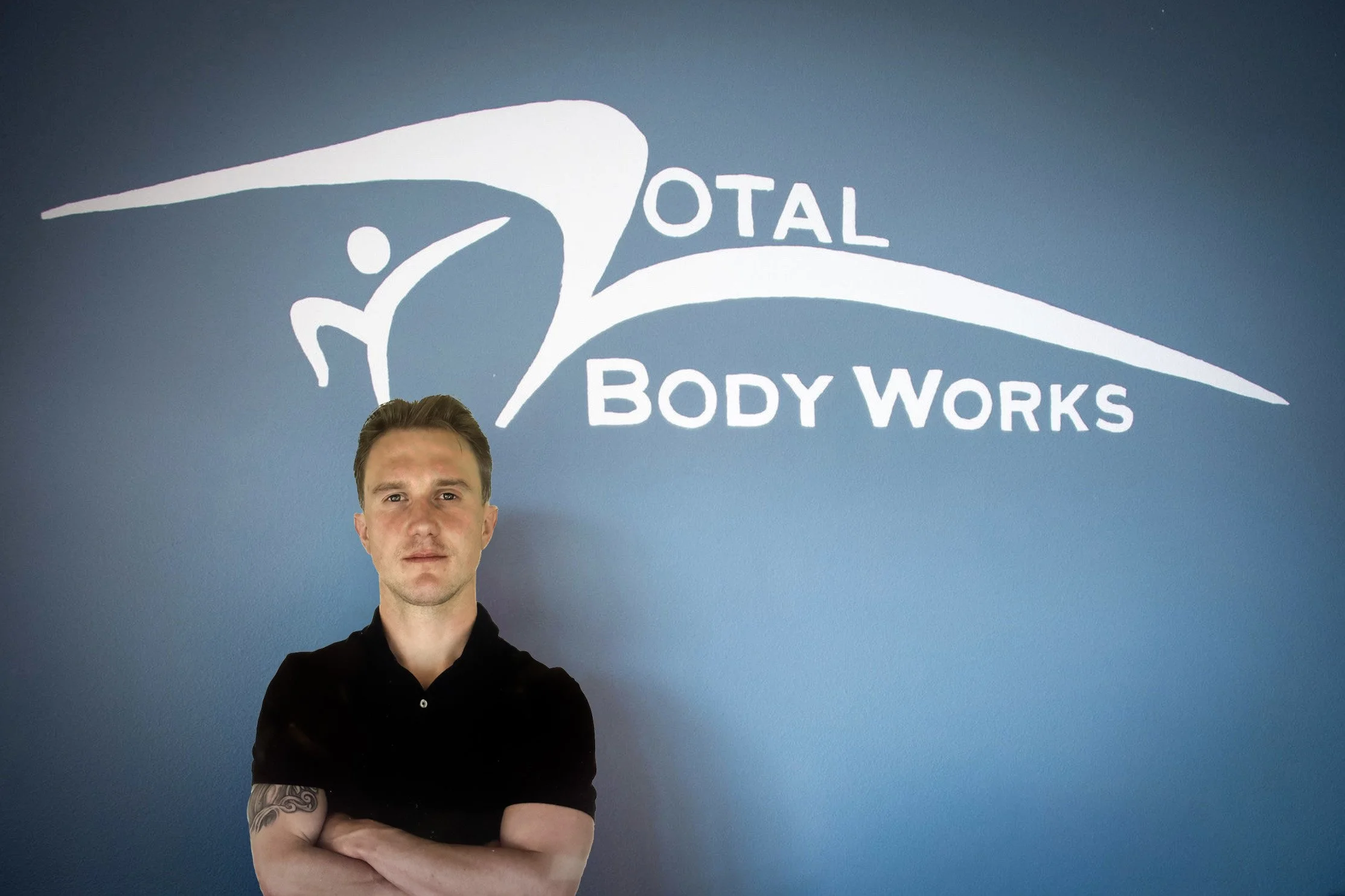 A man with crossed arms standing in front of a wall with a logo and text that reads 'Total Body Works'.