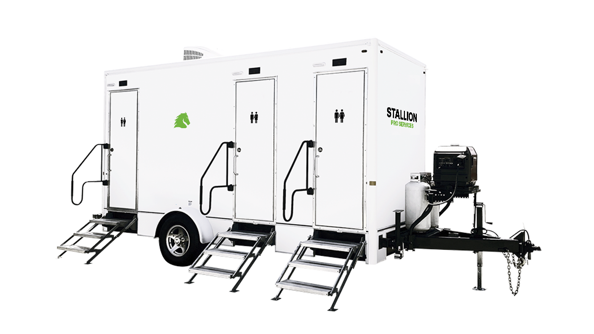 White portable restroom trailer with three doors, black male and female restroom symbols, green horse logo, and green and black "STALLION PRO SERVICES" branding. It has fold-out steps with handrails and an attached generator on a trailer hitch.