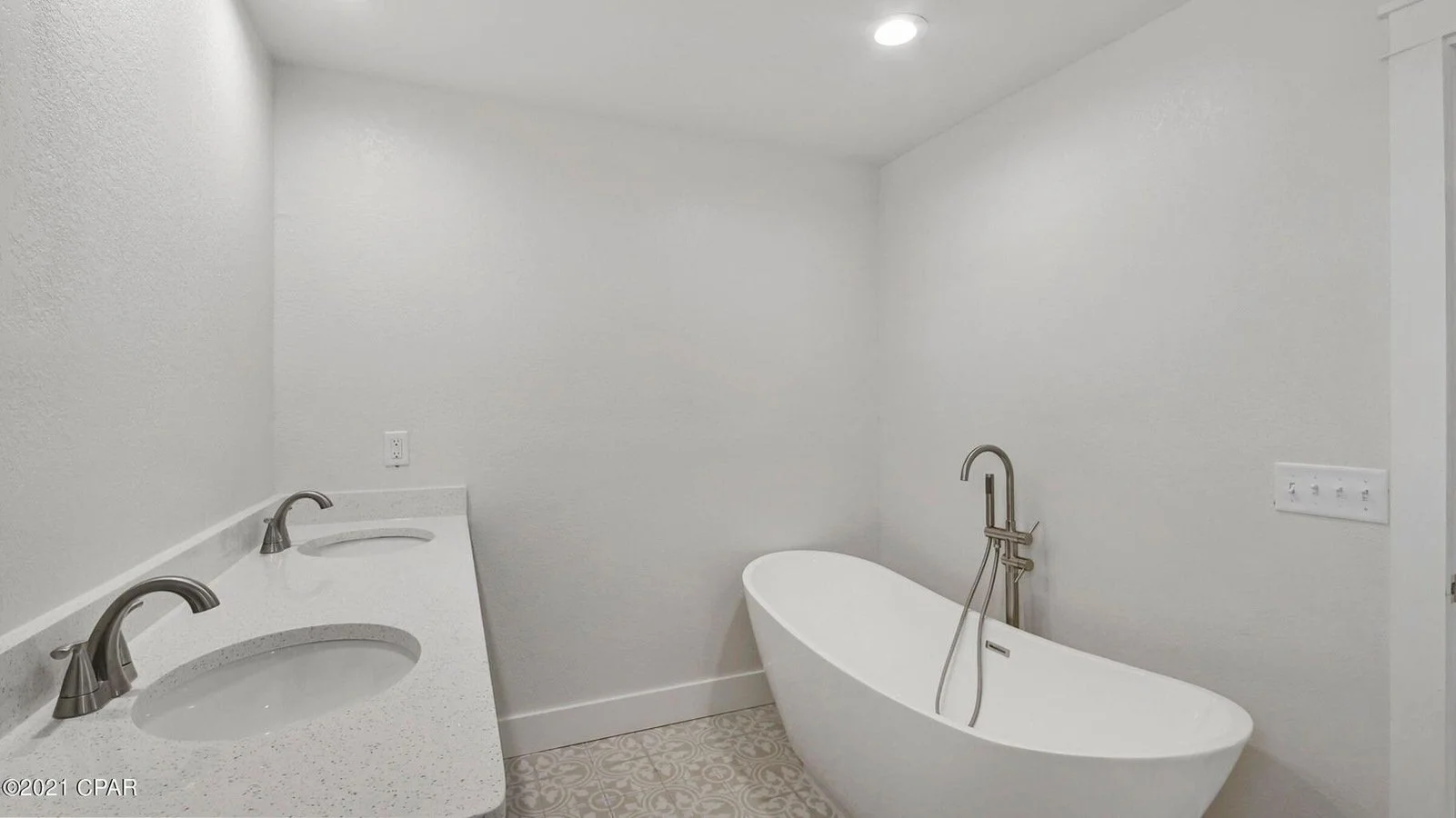 A modern bathroom with two sinks, a free-standing bathtub, and white walls.