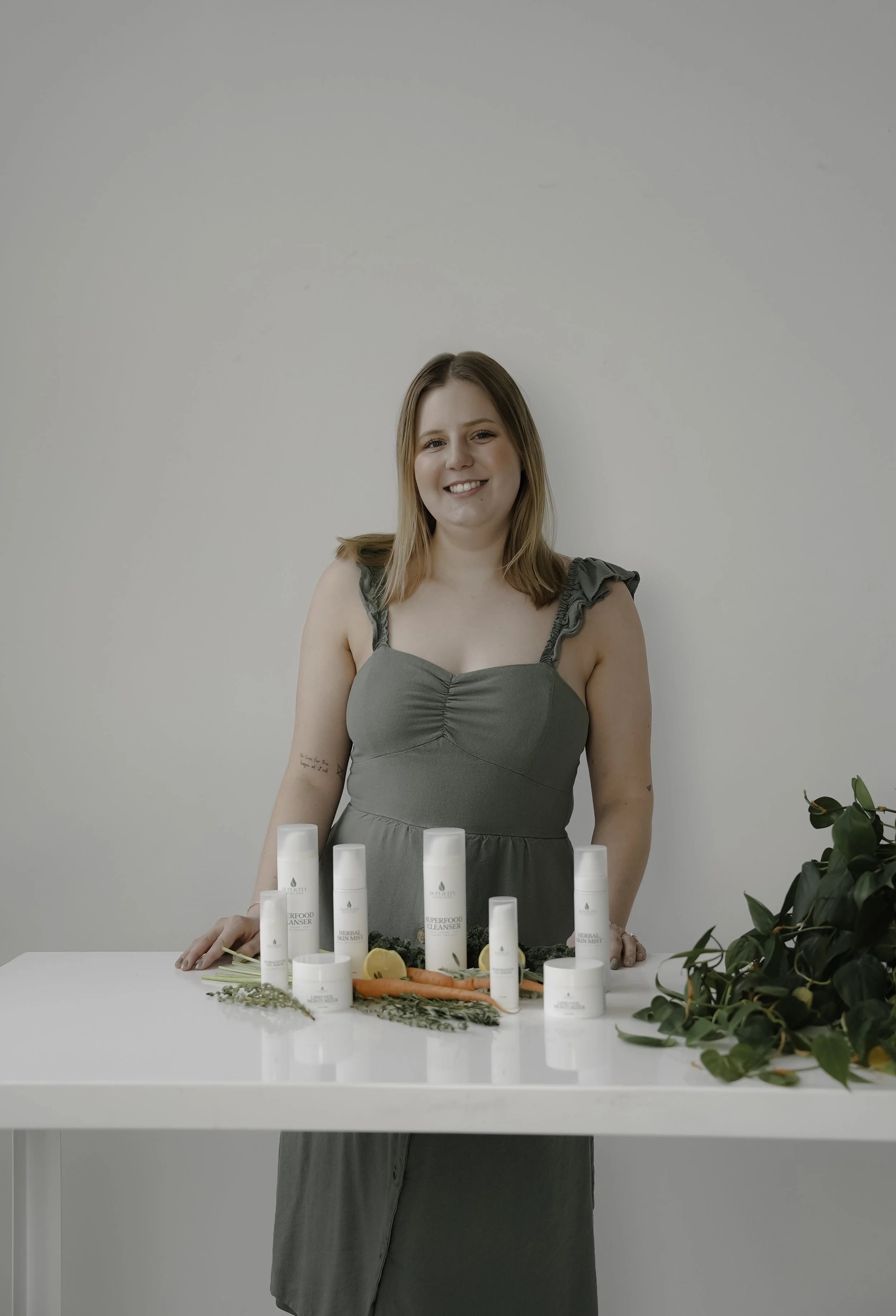 tacoma esthetician, Abby Chandler, is standing behind a white table with a display of multiple skincare products.