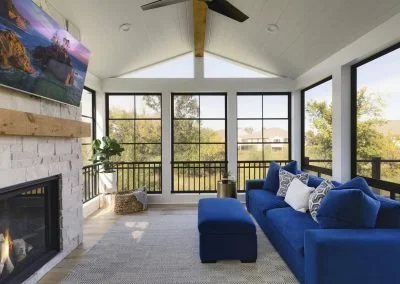 Bright living room with large windows, a blue sofa with pillows, a fireplace, and a ceiling fan.
