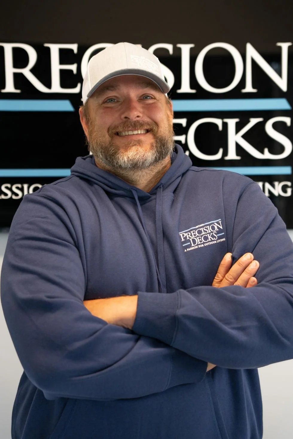 A smiling man with a beard and mustache, wearing a light gray cap and a navy blue hoodie with a 'Precision Decks' logo, standing in front of a black background with large white and blue text reading 'Precision Decks'.