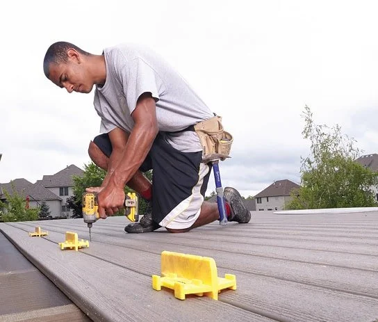 Man installing a wooden deck using power tools outdoors.