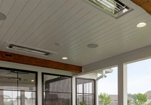 View of an indoor room's ceiling and a glass door leading to an outdoor area with trees and houses.