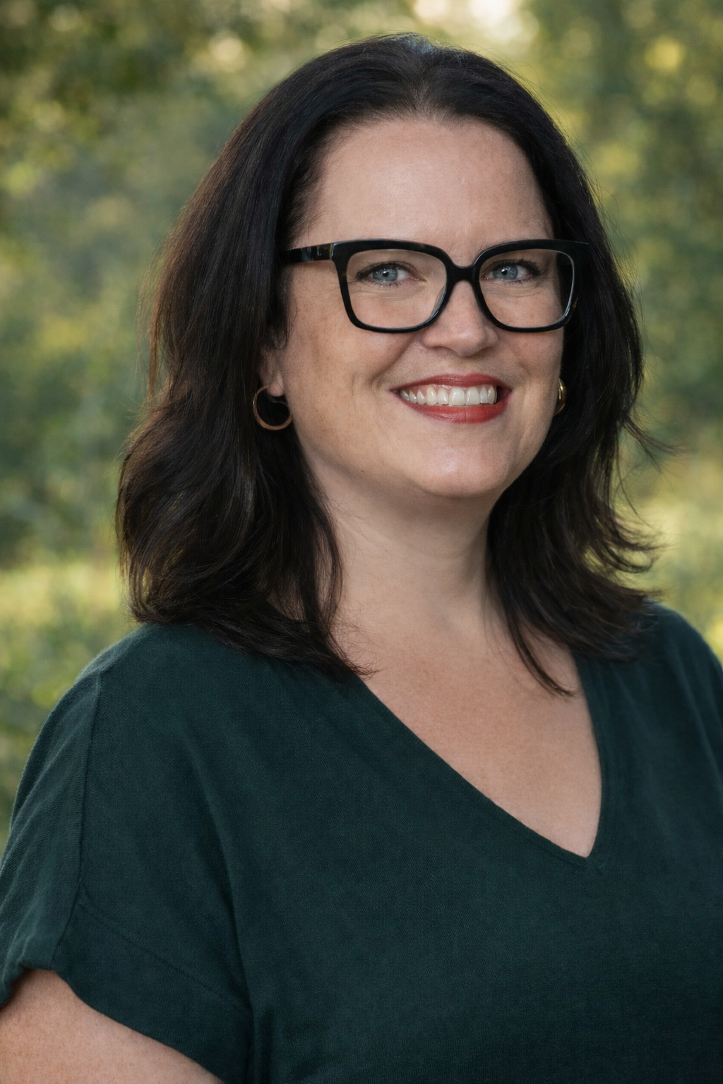 Headshot of Elizabeth Cipolla, she's wearing black rimmed glasses and a green v-neck short sleeve shirt. She has dark hair and blue eyes.