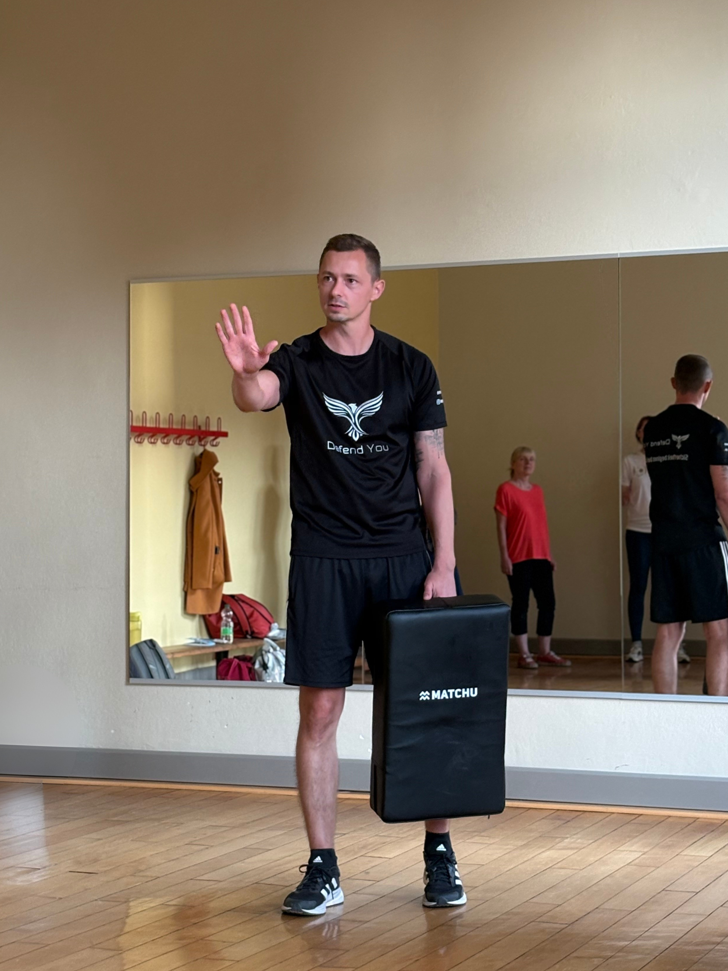 Junger Mann in Sportkleidung macht eine Übung in einem Fitnessraum, die durch einen Spiegel reflektiert wird.