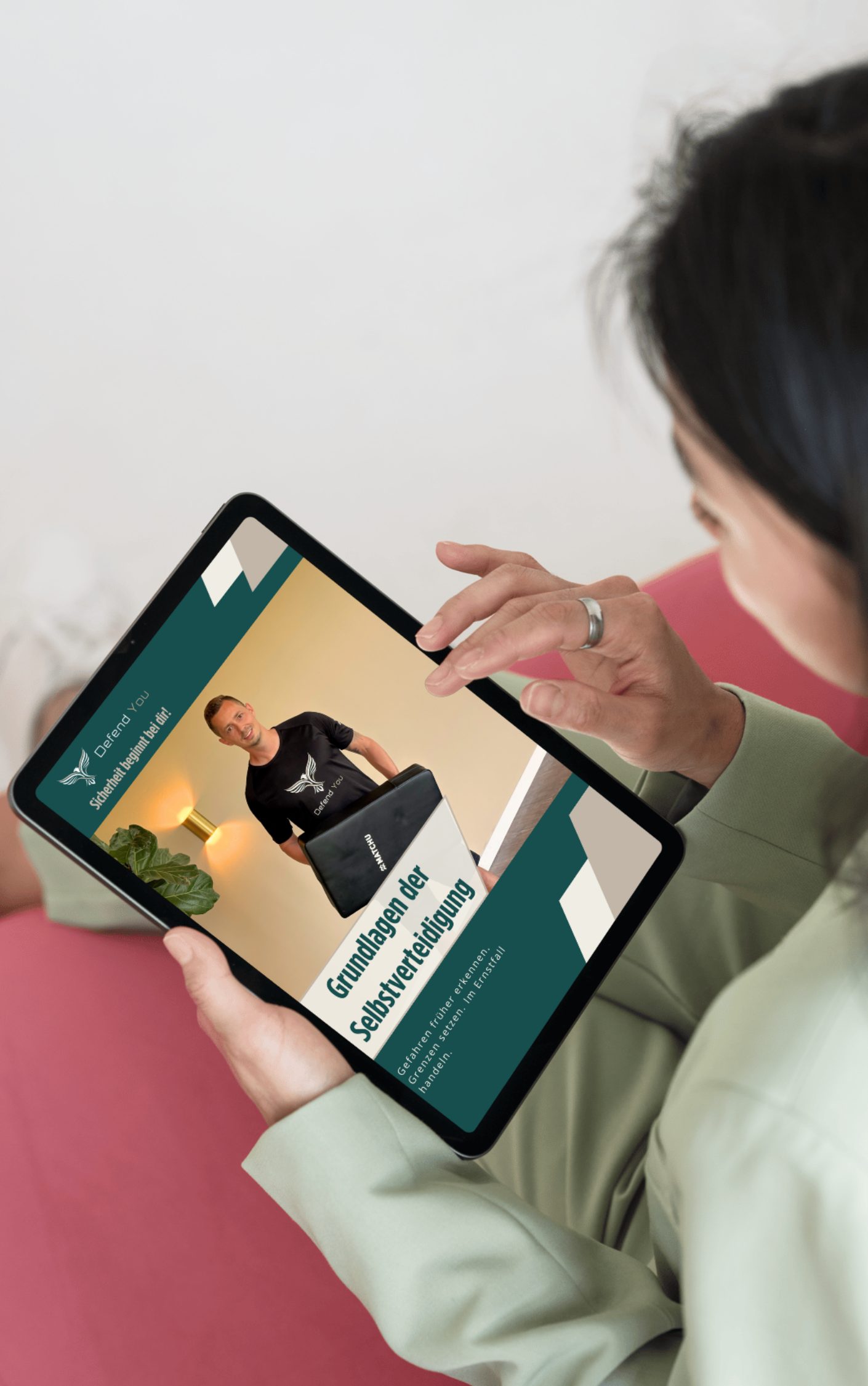 Frau hält Tablet mit einer Präsentation über Selbstverteidigung, sichtbar auf dem Bildschirm. Die Präsentation zeigt einen Mann, der eine Self-Defense-Technik demonstriert, und Text, der die Grundlagen der Selbstverteidigung beschreibt.