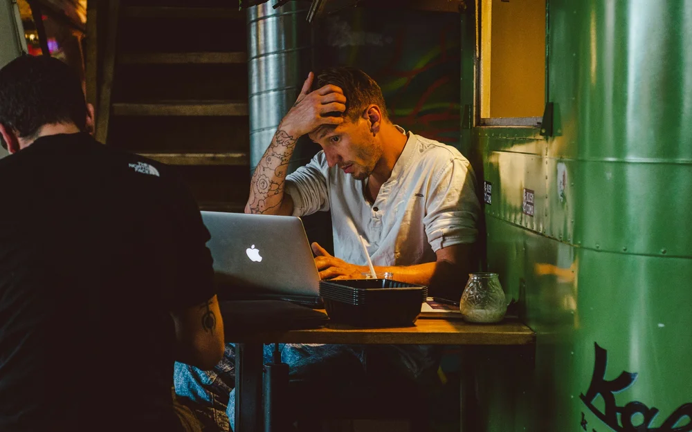 Business owner at a laptop with his head in his hand