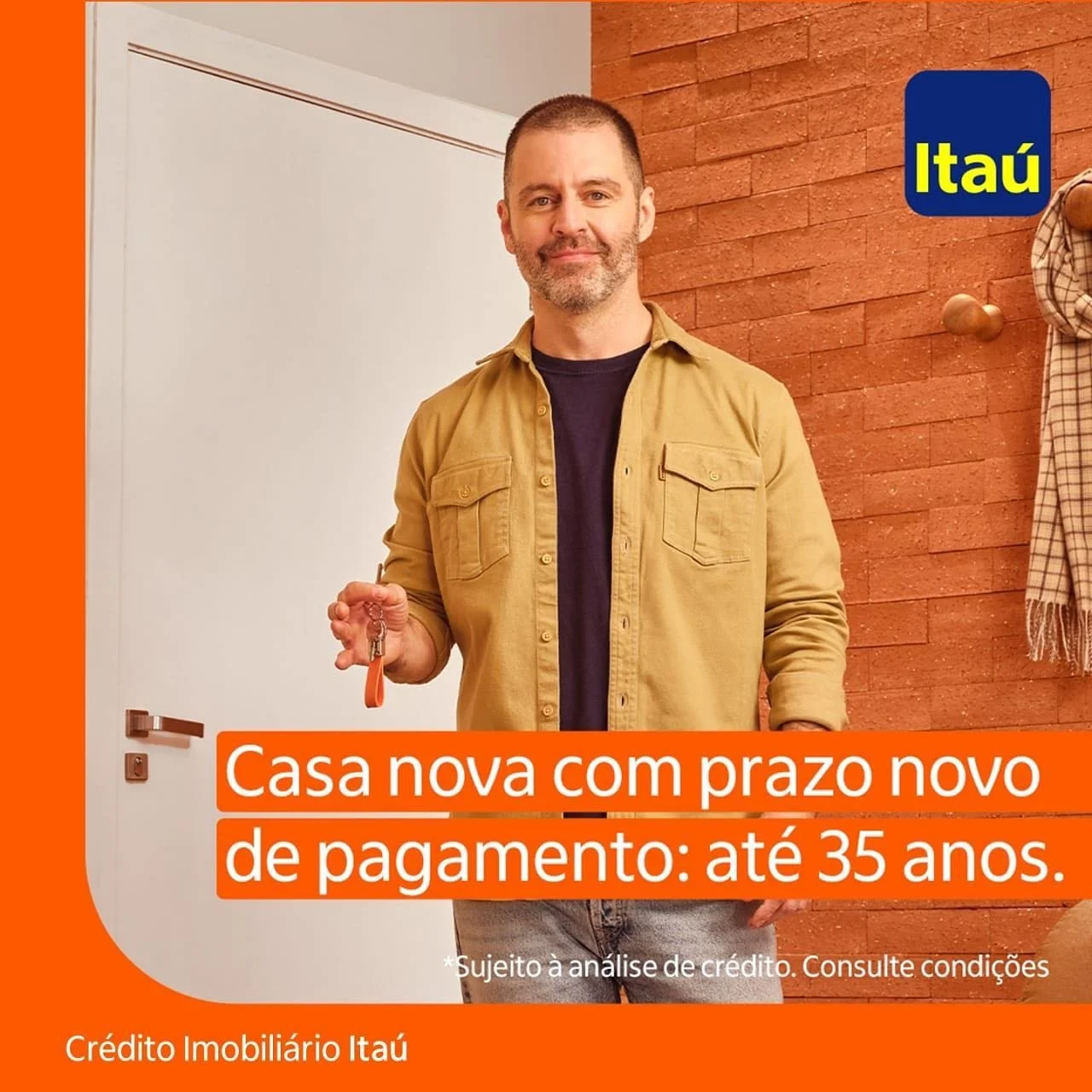 Homem segurando chave de casa, sorrindo, ao lado de parede com logo do Itaú, texto publicitário sobre financiamento de casa nova com prazo de até 35 anos, com condições sujeitas à análise de crédito