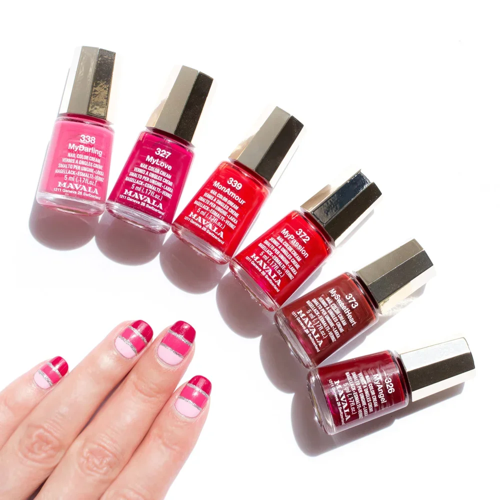 Fünf Flaschen Nagellack in verschiedenen Rottönen, daneben eine Hand mit Fingernägeln in zweifarbigem Nageldesign mit rosa und roten Streifen.