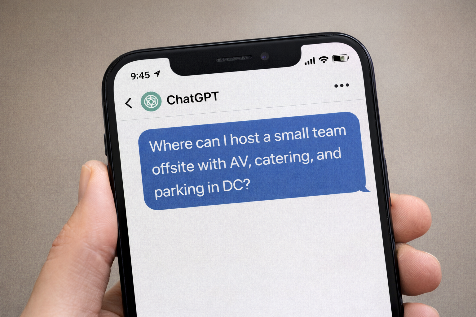 A smartphone screen displaying a ChatGPT conversation where a meeting planner asks specifically for a 'small team offsite with AV, catering, and parking in DC.