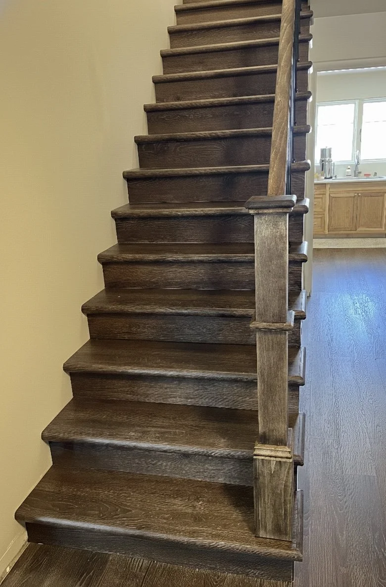 Wooden staircase with a dark stain, leading upstairs in a home interior.