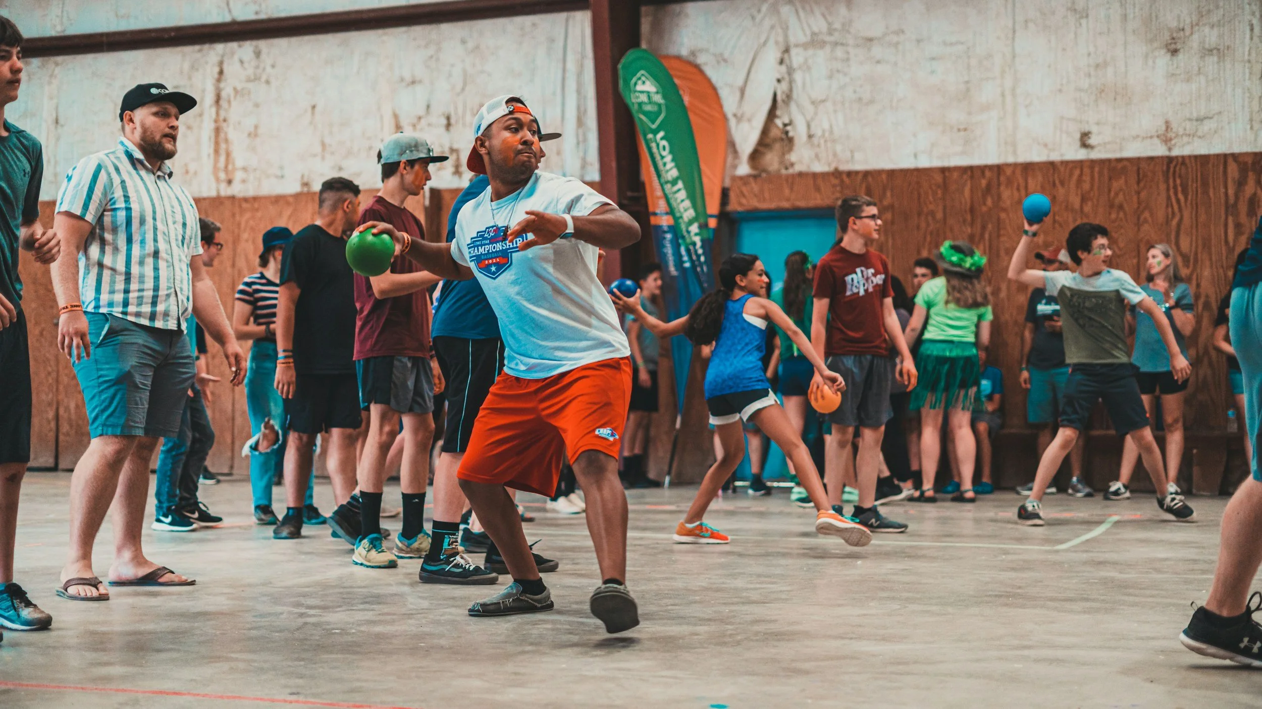 Children and teenagers playing dodgeball in an indoor gym.
