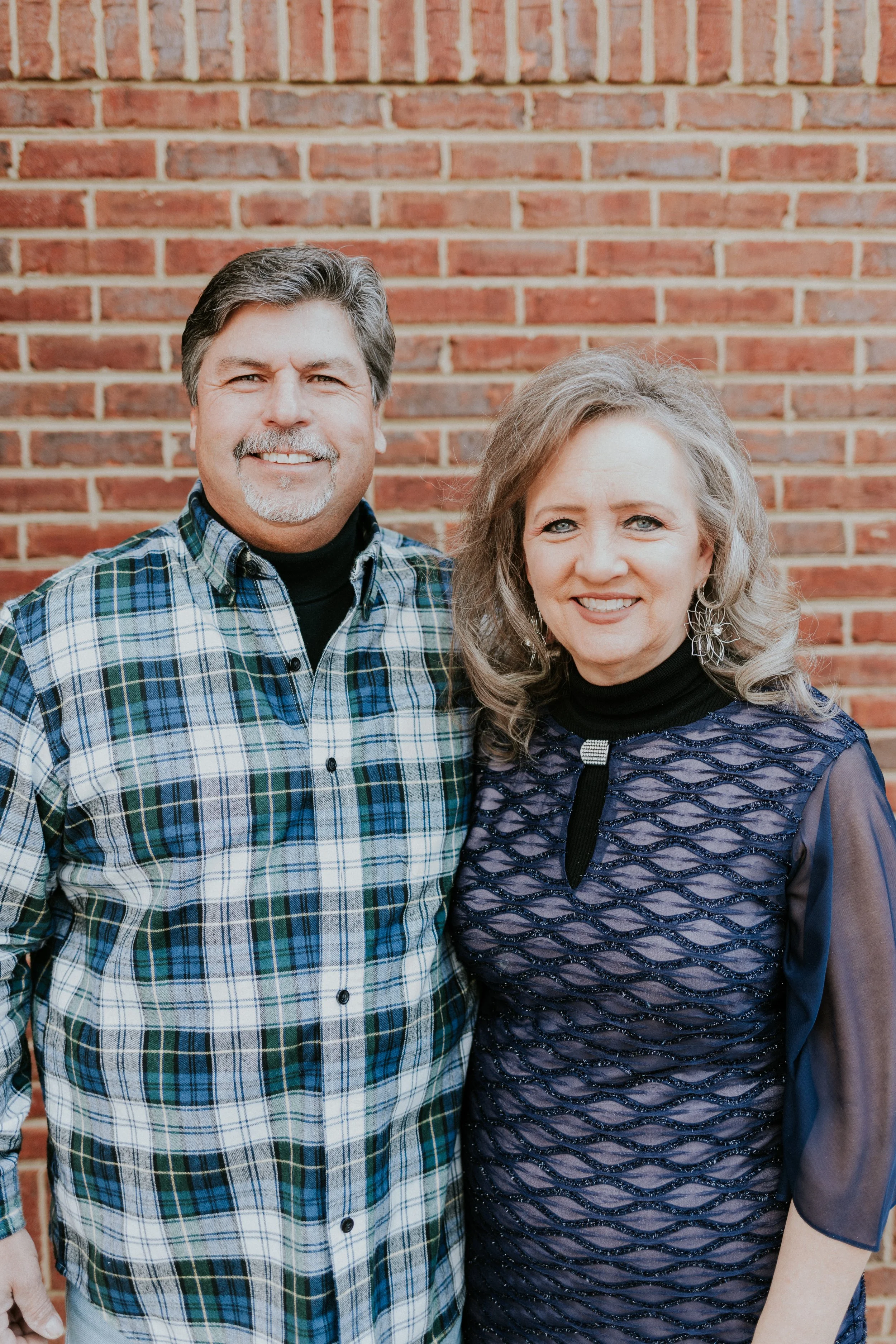 Smiling woman and smiling man wearing a plaid shirt.