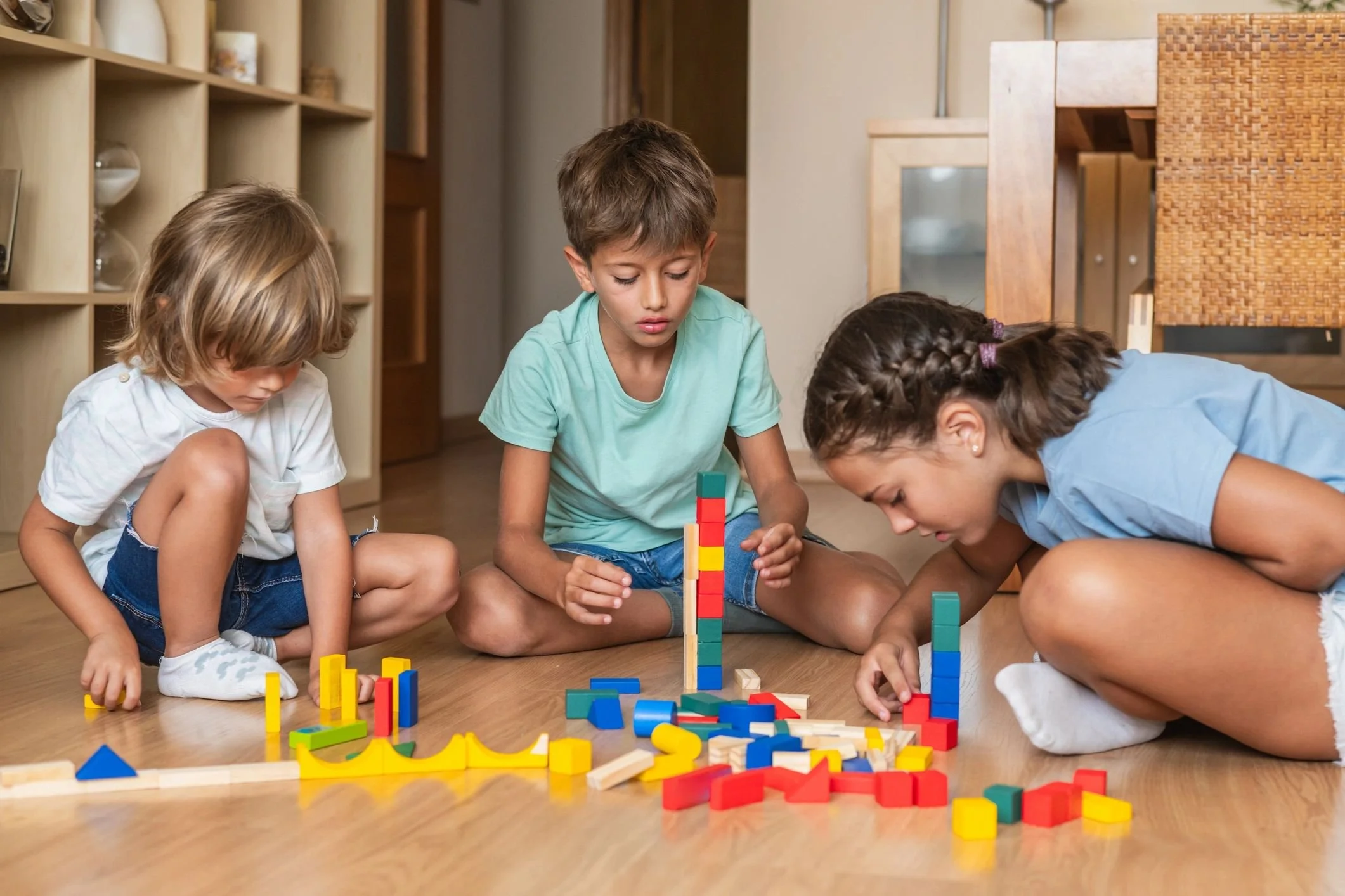 Two male presenting children and one female presenting playing with colorful blocks