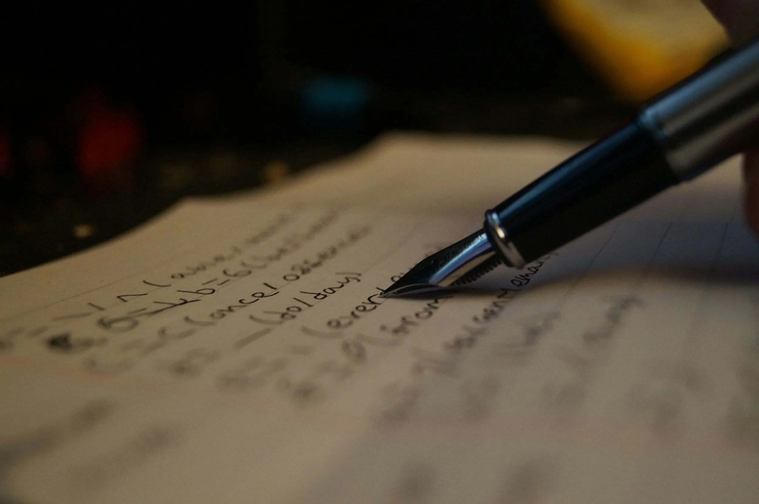 Close-up of a black pen resting on handwritten notes or a to-do list on paper.