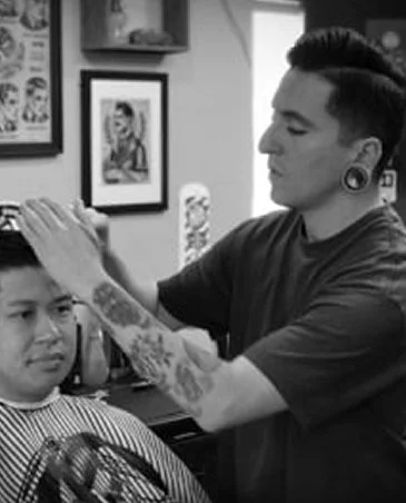 A person getting a haircut from a barber in a barbershop.