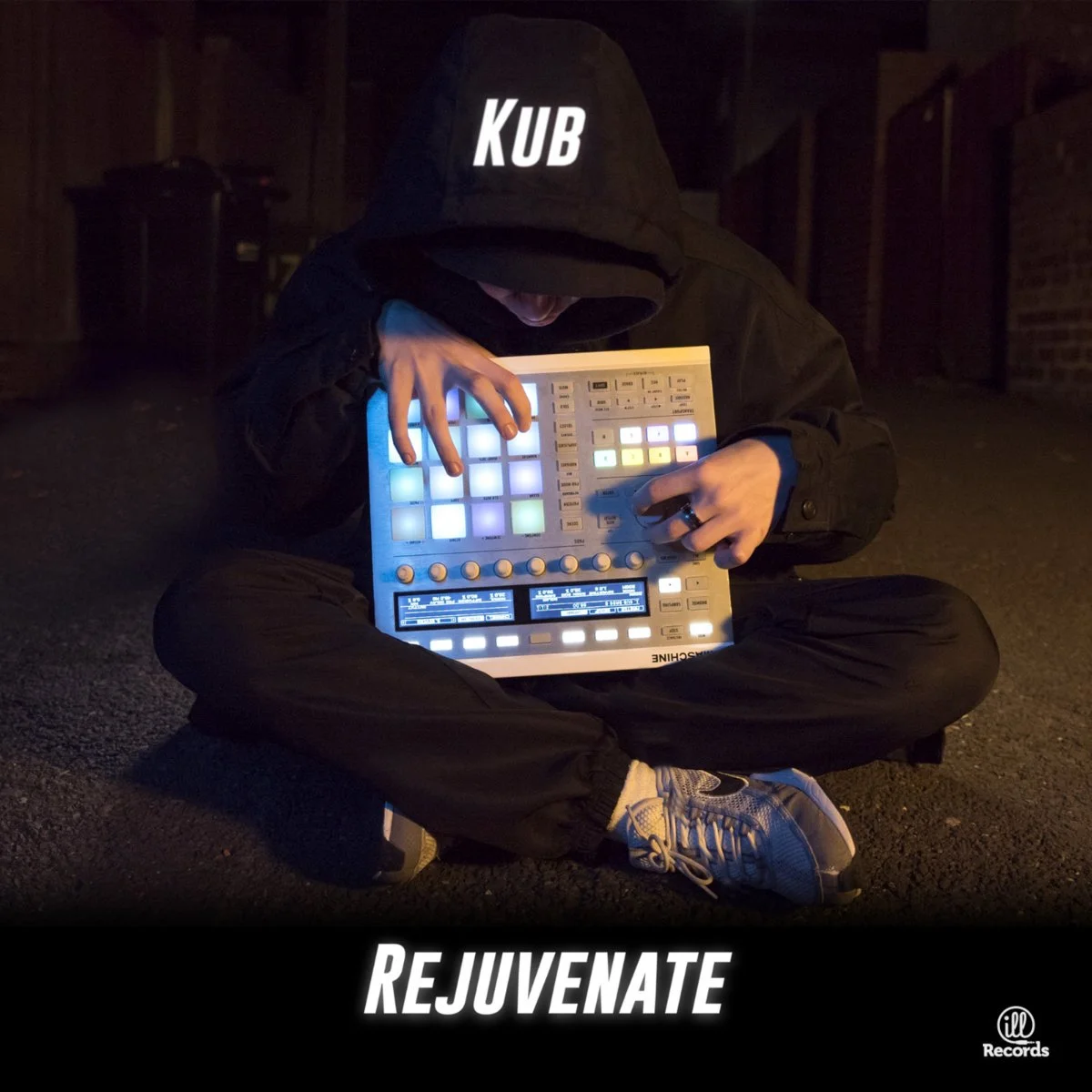 Person in hoodie with 'KUB' on it, sitting cross-legged on the ground at night, using a music production controller with glowing pads, in an urban alleyway, with the words 'REJUVENATE' at the bottom and 'ill Records' logo.