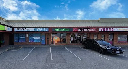 Empty parking lot in front of a strip mall with stores and a black car parked.