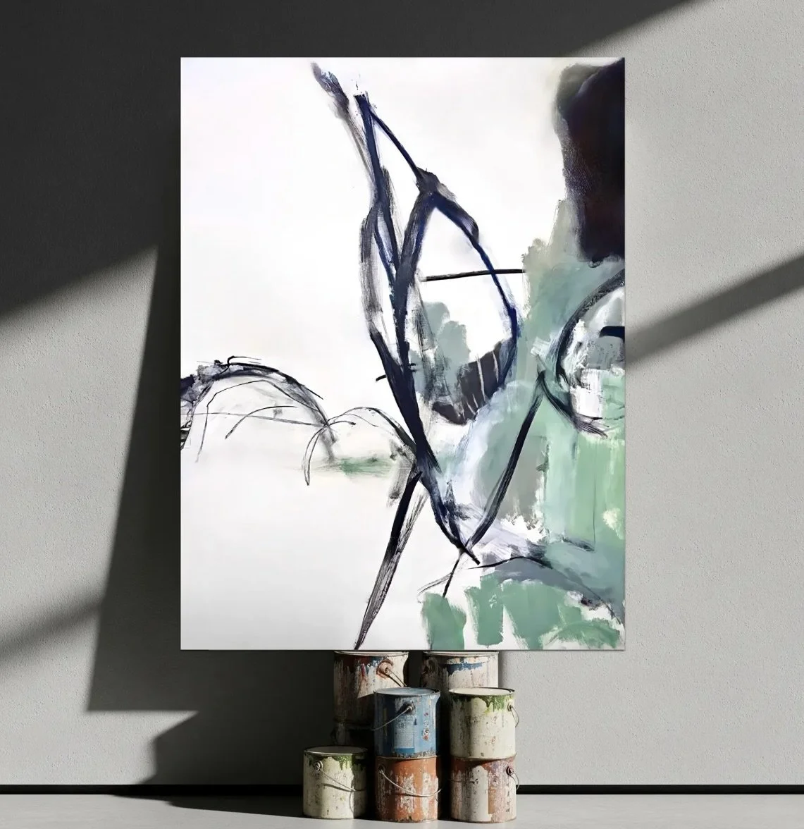 Abstract painting on canvas displaying black and green brushstrokes, mounted on a stand with paint cans underneath, casting shadows on a gray wall. Jenn Thompson, MFA Colorado State University - BFA University of Colorado at Denver - Fort Collins