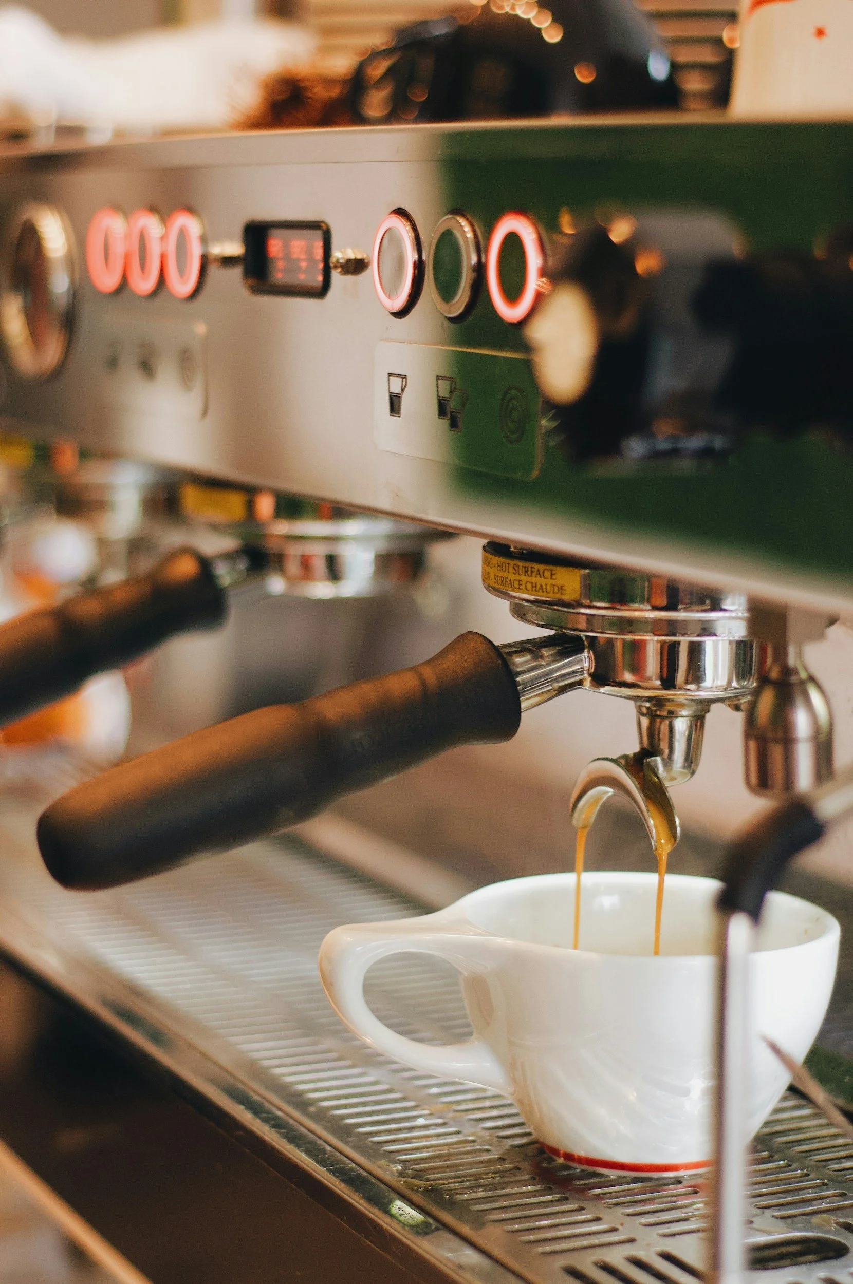 A close-up of a commercial espresso machine brewing coffee into a white mug.