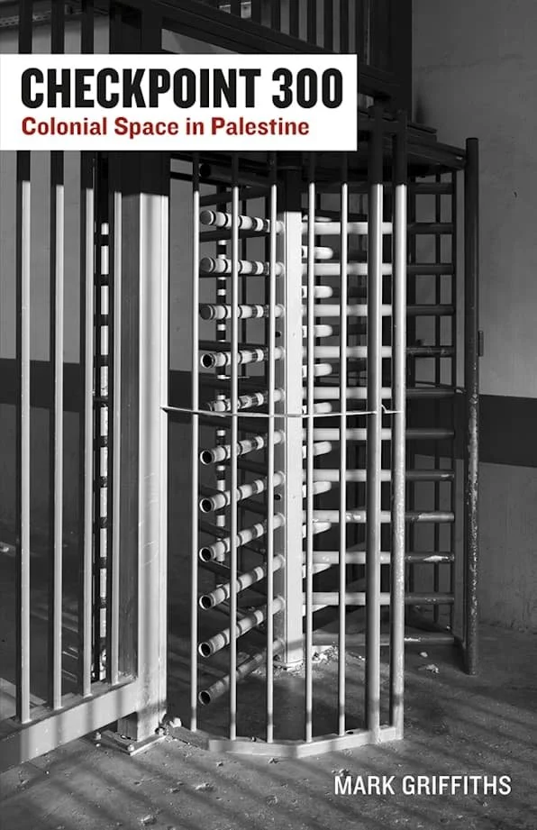 A black and white photograph of a security checkpoint with a metal turnstile and a sign that reads 'CHECKPOINT 300 Colonial Space in Palestine' with the name 'Mark Griffiths' at the bottom.