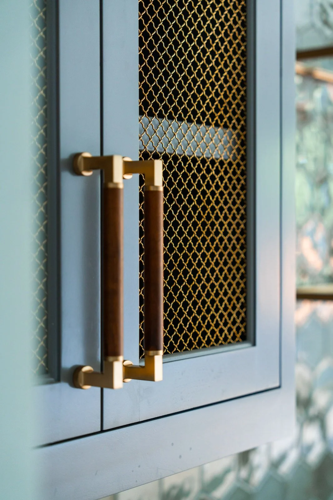 Close-up of a cabinet with blue doors, gold handles, and a gold mesh panel showing inside shelves with towels.