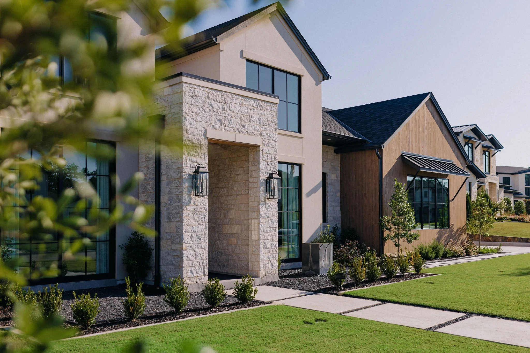 Modern residential house custom designed by Providential Custom Homes with landscaped front yards and walkway, daylight.