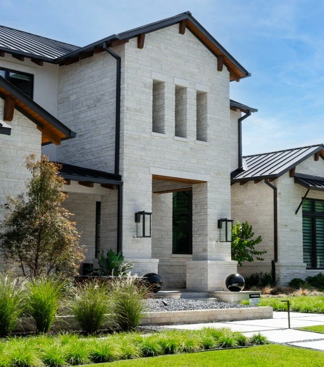 Custom luxury house in Argyle, TX with stone exterior, large entrance, and landscaped front yard.