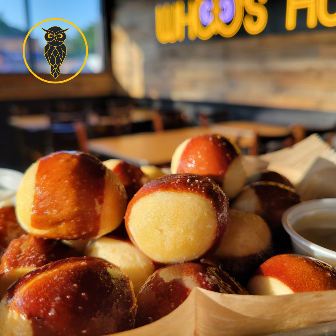 Close-up of freshly baked pretzels with a dipping sauce on the side in a bakery or restaurant setting.