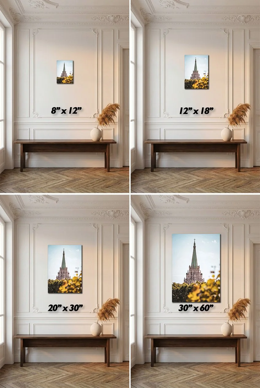 Four images showing the same picture of a cathedral with a tall spire, each framed with different sizes: top left 8x12 inches, top right 12x18 inches, bottom left 20x30 inches, bottom right 30x60 inches. The pictures are hung on a white wall with decorative molding, above a wooden table with a vase containing dried plants, in a room with wood flooring and large windows.