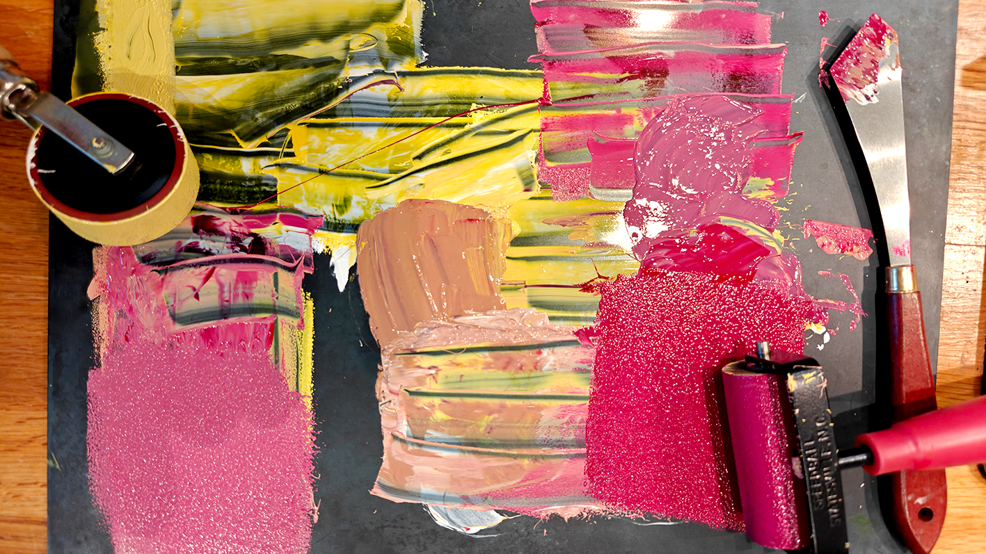 Gros plan d'une palette de peinture avec des taches de différentes couleurs, y compris roses, jaunes, verts, beige, et des outils artistiques à proximité sur une surface en bois.