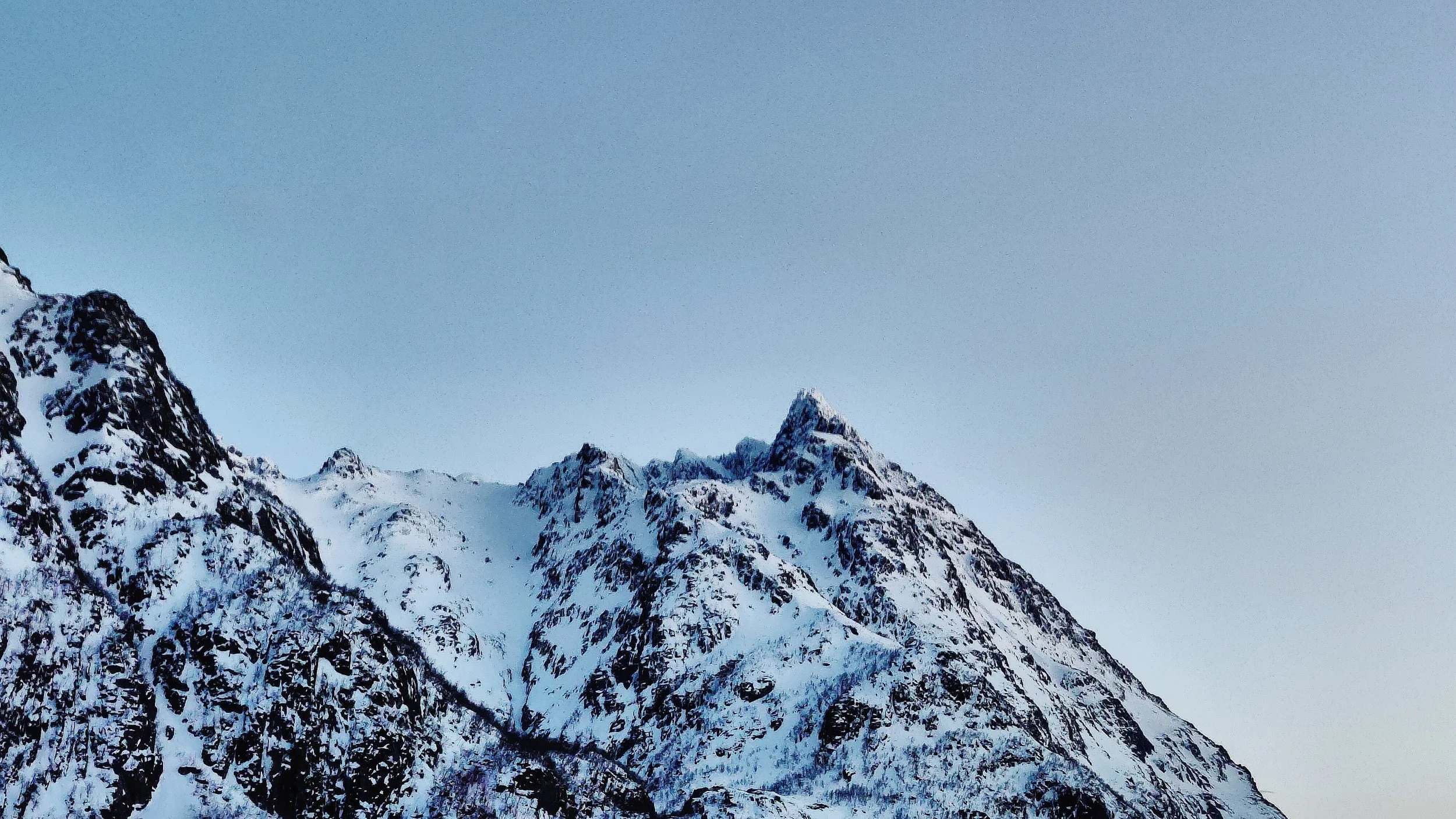 Montagnes enneigées sous un ciel clair, sommet pointu visible.
