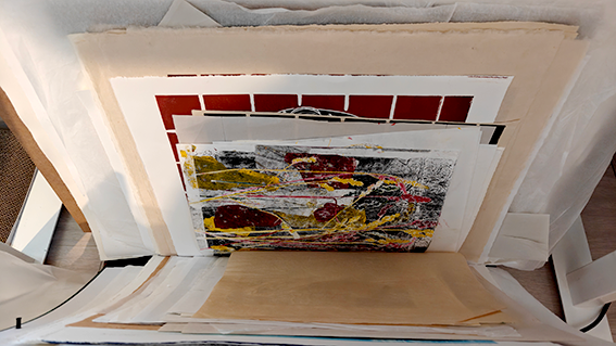 Photographies empilées dans un classeur ou un portfolio, dont certaines sont déformées ou endommagées.